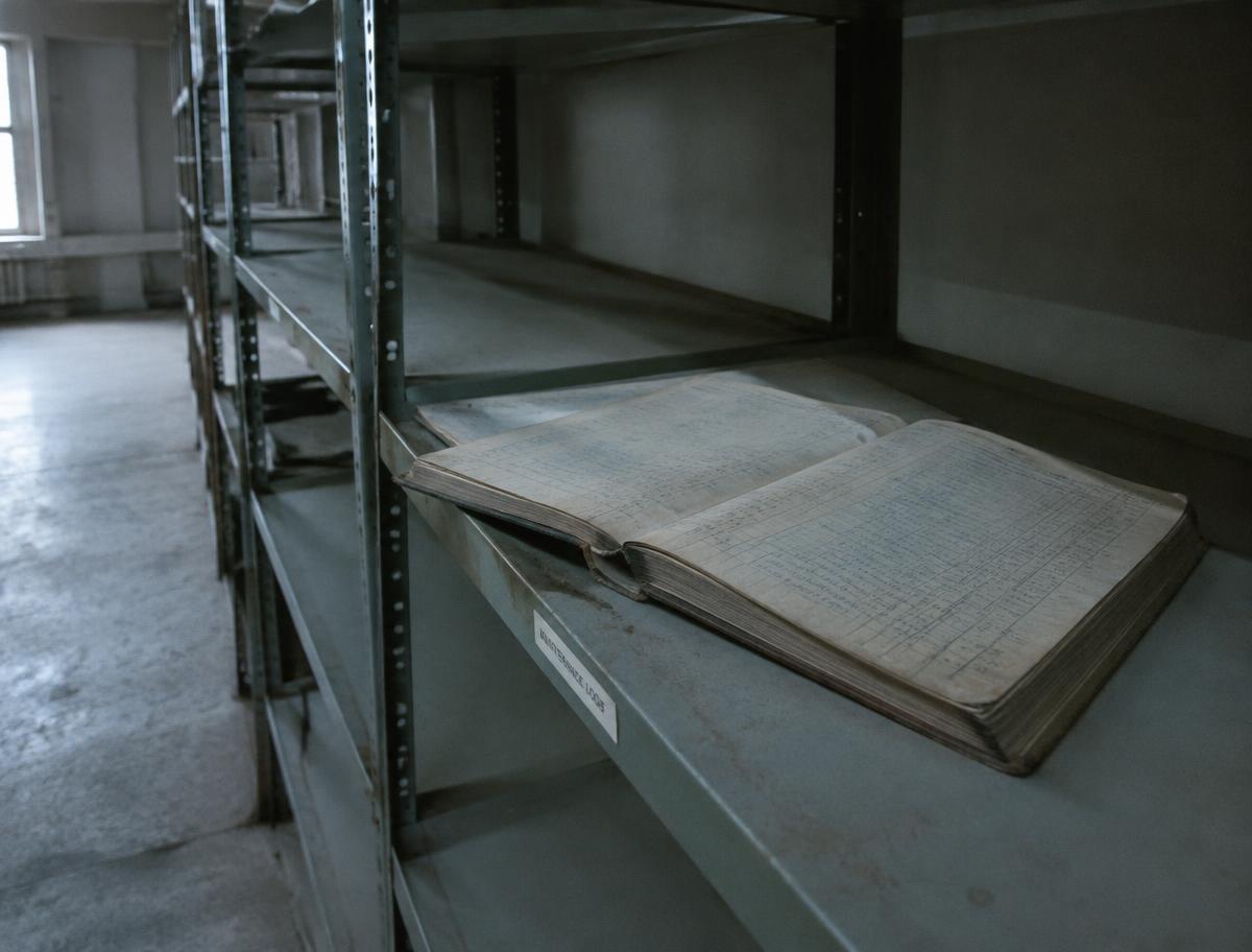 Livro de registros de manutenção abandonado em prateleira metálica vazia
